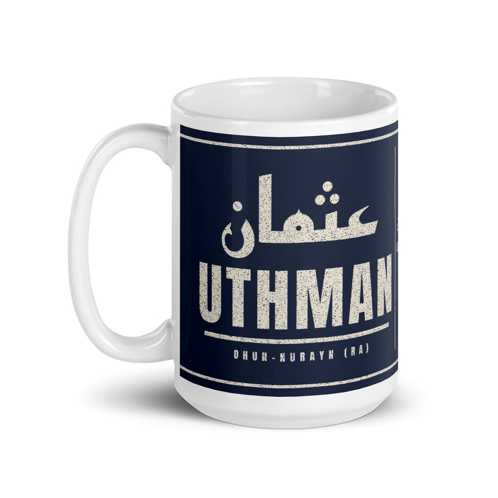 Muslim By Nature™ LEGACIES: MEN №03 Uthman (RA) 15oz white mug – navy wrap with Kufic Arabic name and UTHMAN in cream – handle on left